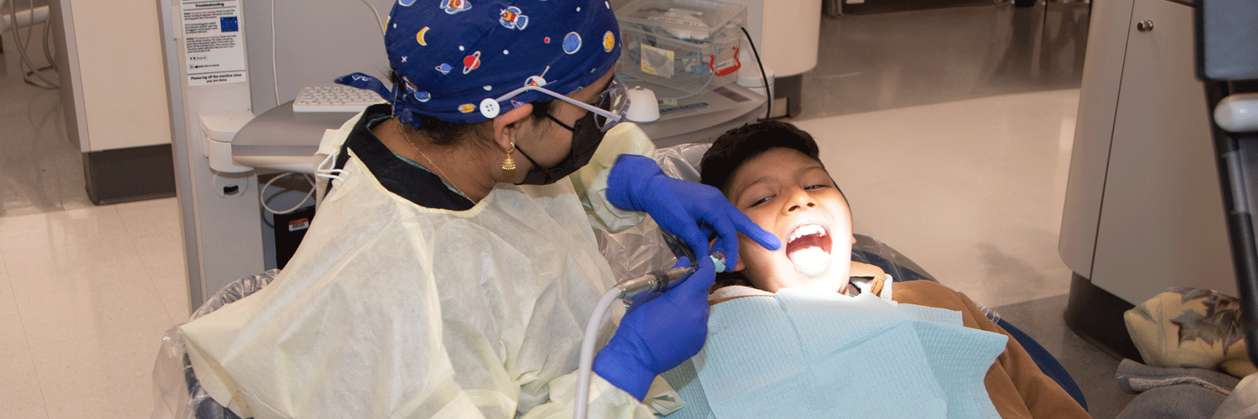 Woman performs dental care on a child in a clinical setting