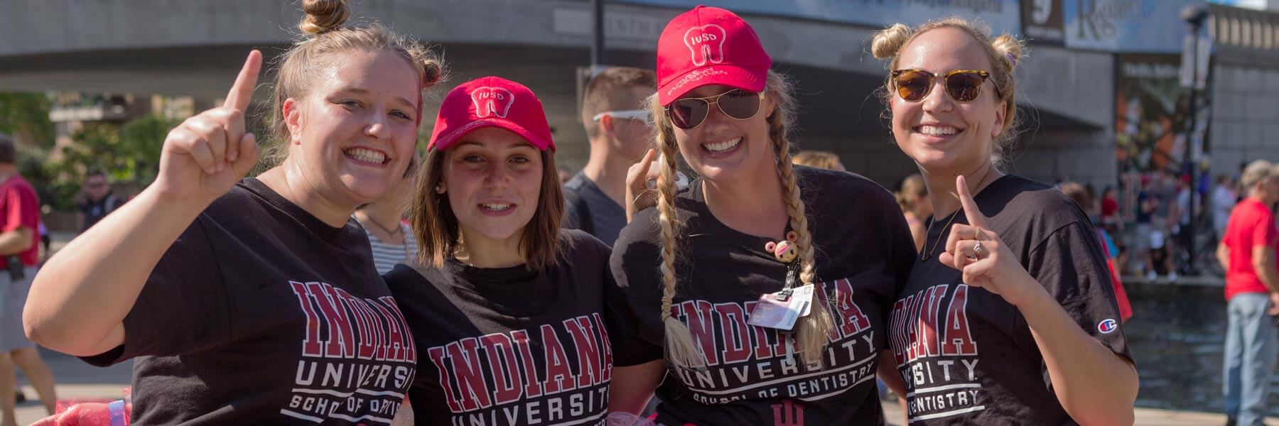 Four female dentistry students smile and show their school spirit at a game.