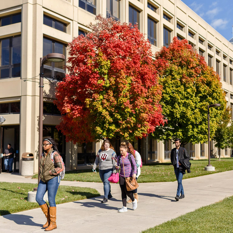IUPUI students walk down the sidewalk past a campus building.